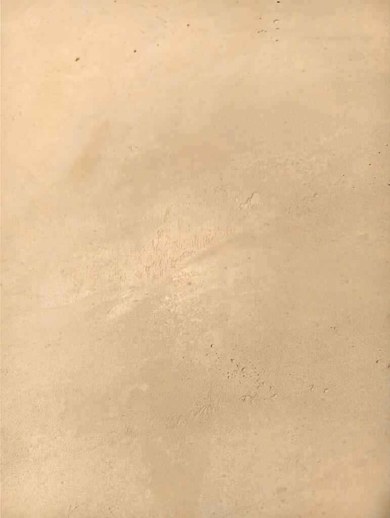 Nahaufnahme einer sandfarbenen Mikrozementoberfläche mit feiner Struktur.